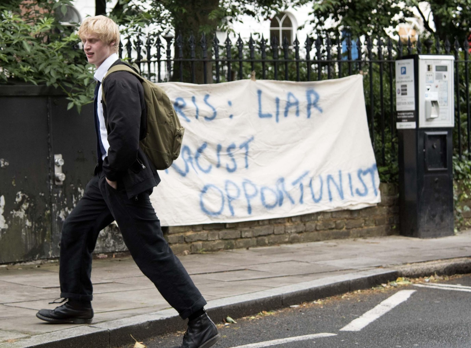 Theodore was pictured in school uniform walking past a protest by his home 