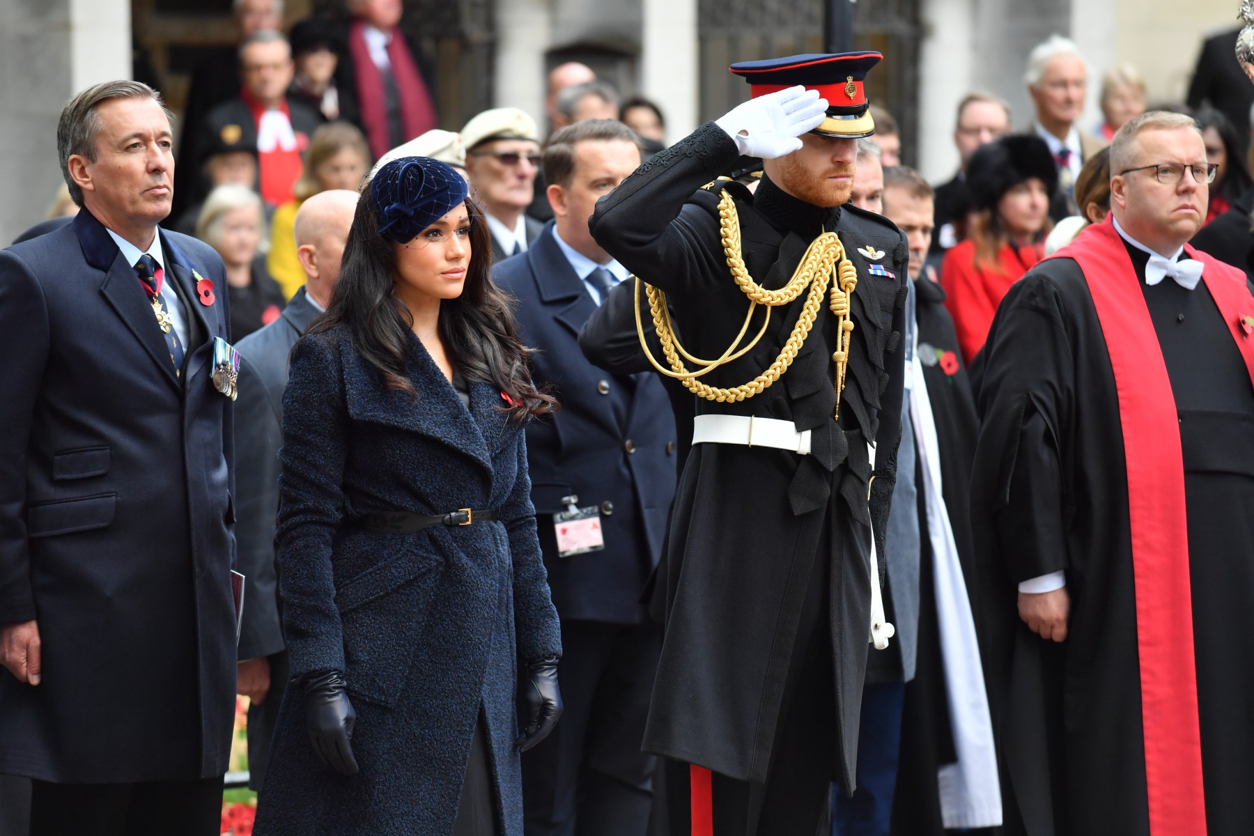 Prince Harry salutes as Meghan stands by his side