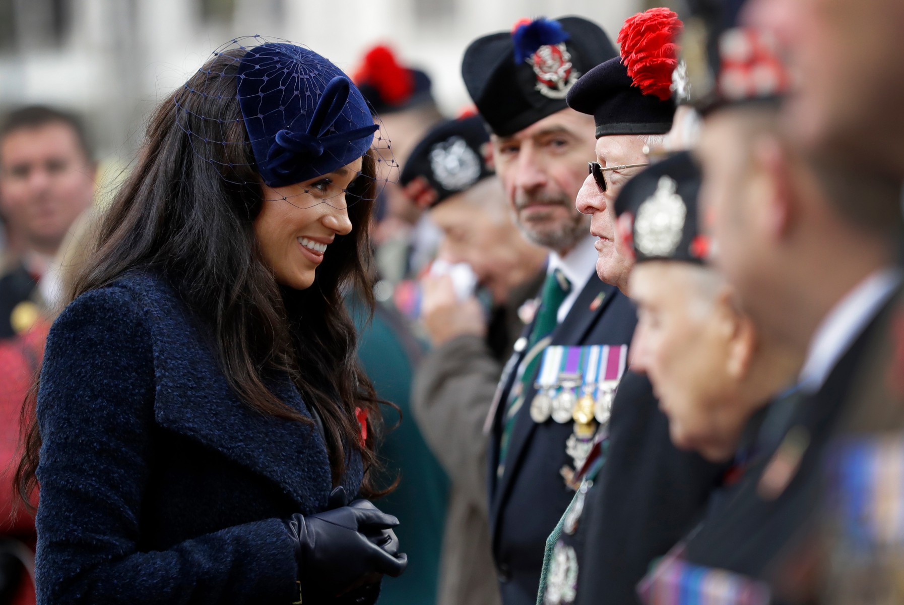 Meghan Markle smiles as she speaks to a veteran after the service