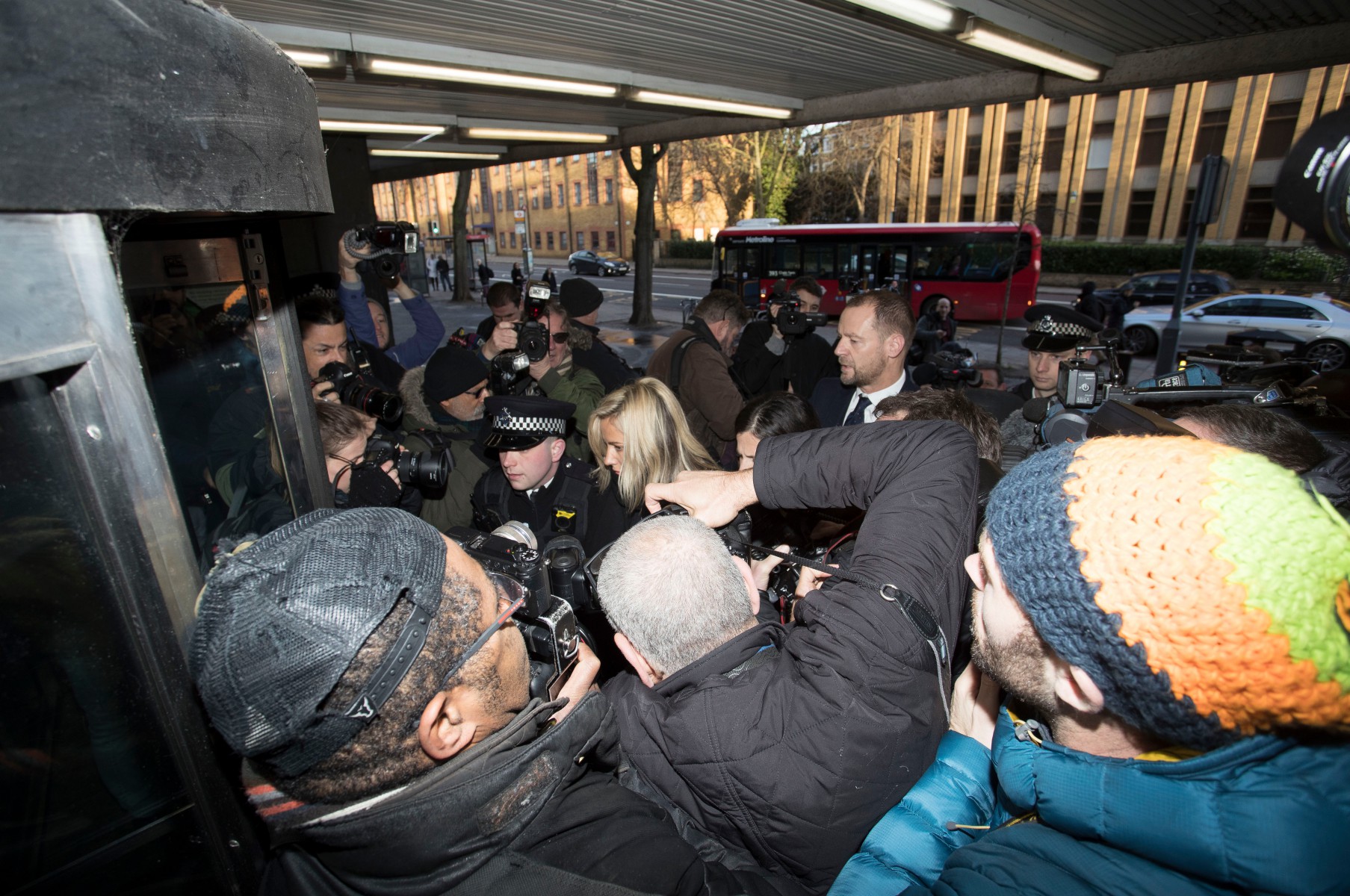 Police push their way through photographers as Ms Flack walks into court