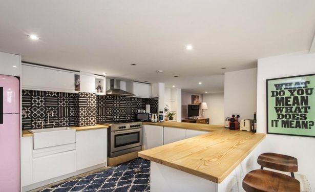 The kitchen features wooden worktops and geometric tiles