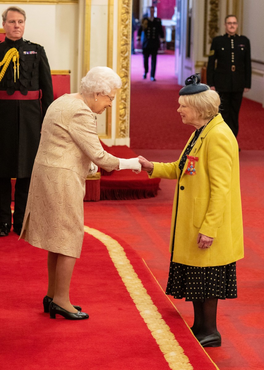 The Queen today wore gloves for the Buckingham Palace ceremony -pictured shaking hands with actress Wendy Craig