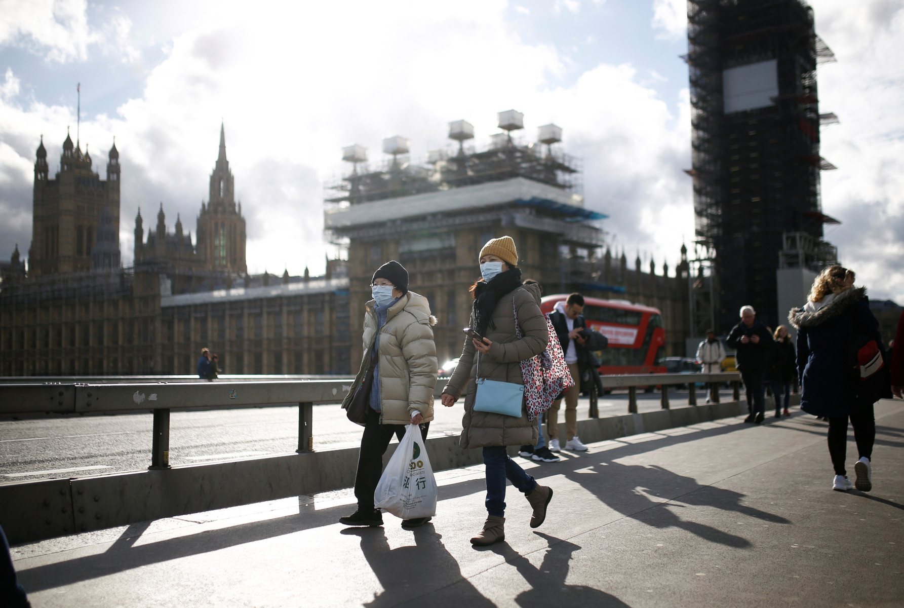 People in face masks walk past the Houses of Parliament today