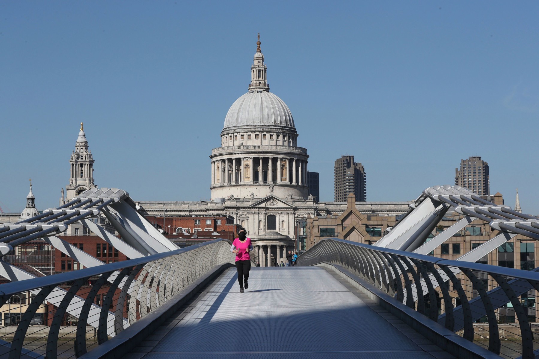 A lone jogger crosses London's Millennium Bridge in front of St Paul's Cathedral