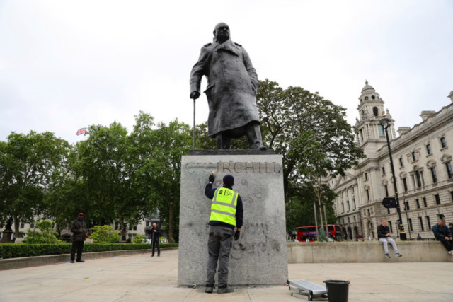 A worker cleans graffiti from the plinth of the statue of Sir Winston Churchill