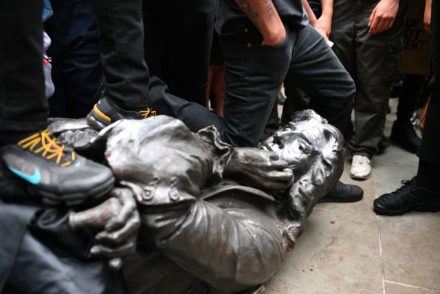 Protesters kneel on the neck of the statue after it was toppled in Bristol